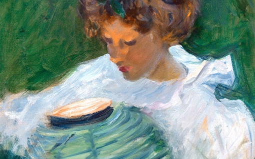 A person in a white dress sits outdoors near green foliage with a round object beside them.