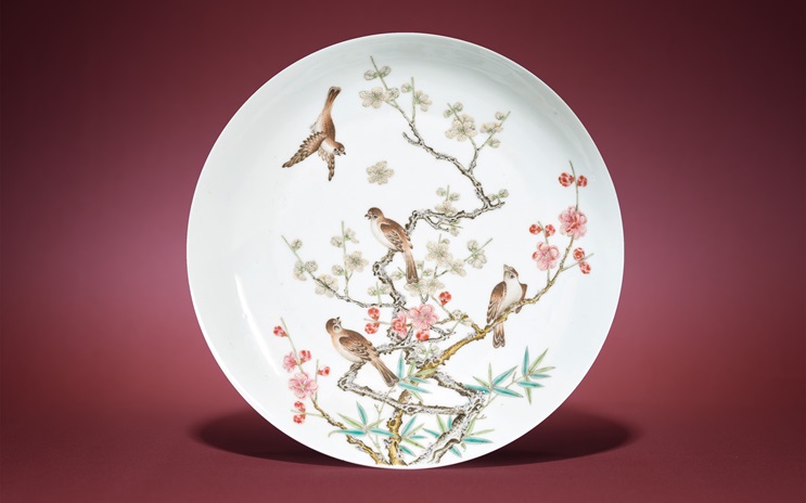A decorative plate featuring a detailed illustration of birds perched on flowering branches.