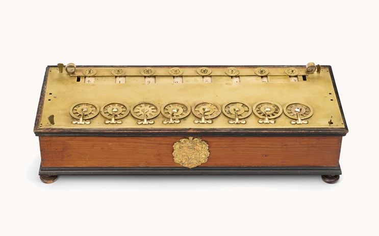 Antique wooden and brass calculating machine with multiple dials, set in a wooden case with brass details and ornamental design.