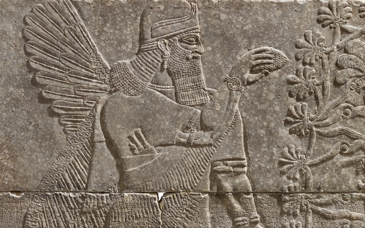 Ancient stone relief of a winged figure with a beard, holding an object near a stylized tree.