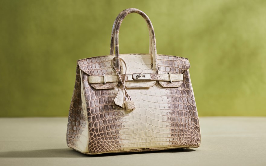 A luxury crocodile leather handbag with a beige and brown gradient is displayed on a surface.