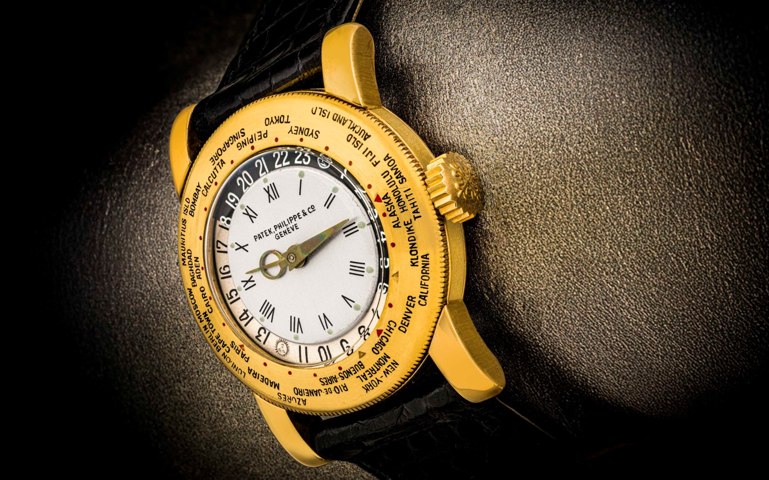A close-up of a luxurious golden wristwatch with intricate detailing and multiple dials set against a textured black background.